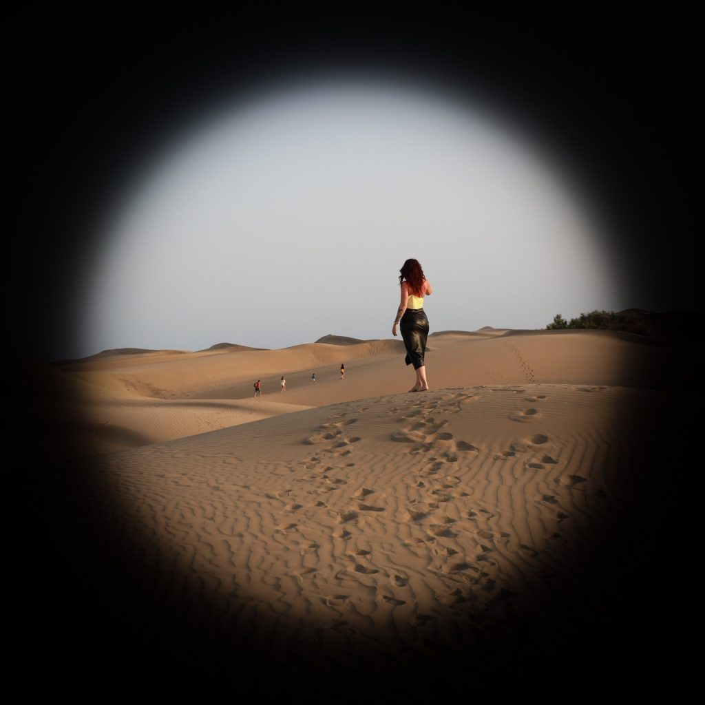 foto dat Danielle in de verte tuurt op een zandvlakte.