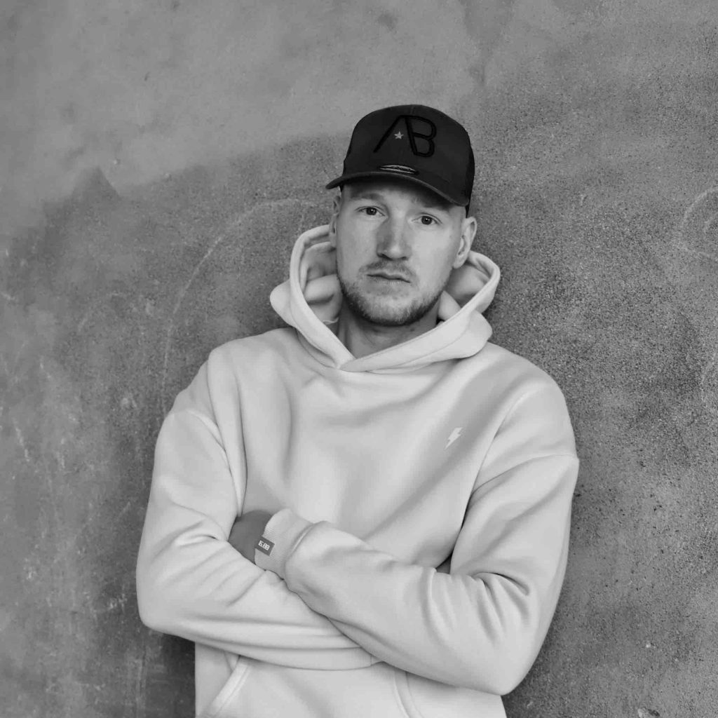 Zwart wit portretfoto van man met pet op en armen over elkaar. Fotografie door Ont.Daan