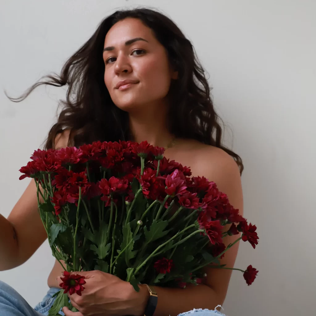 Kleur portret van vrouw met grote bos donkerrode bloemen. Fotografie door Ont.Daan